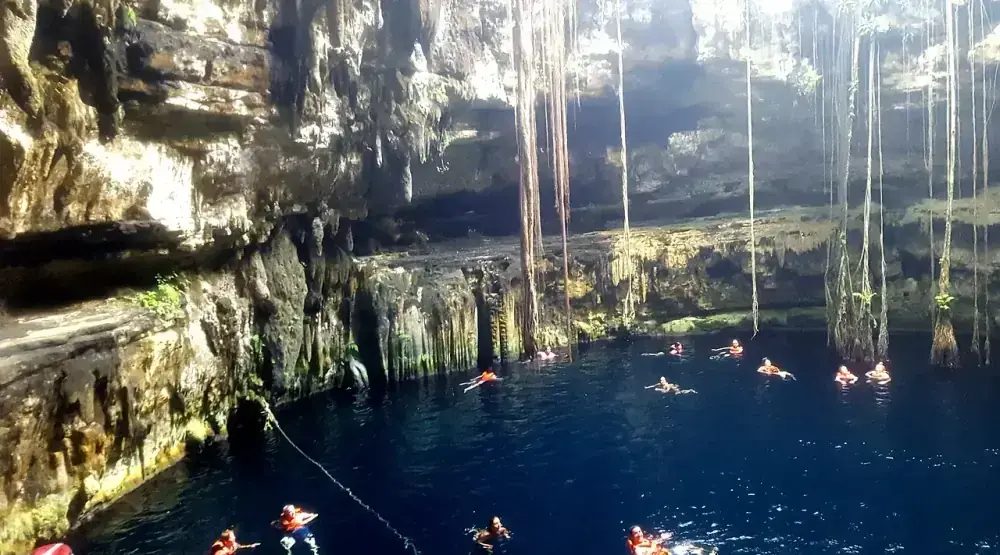 Cenote Oxman Valladolid Mexico with hanging vines and rope swing over clear turquoise water at Hacienda San Lorenzo