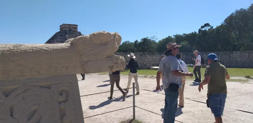 Kukulkan serpent head sculpture with visitors at Chichen Itza