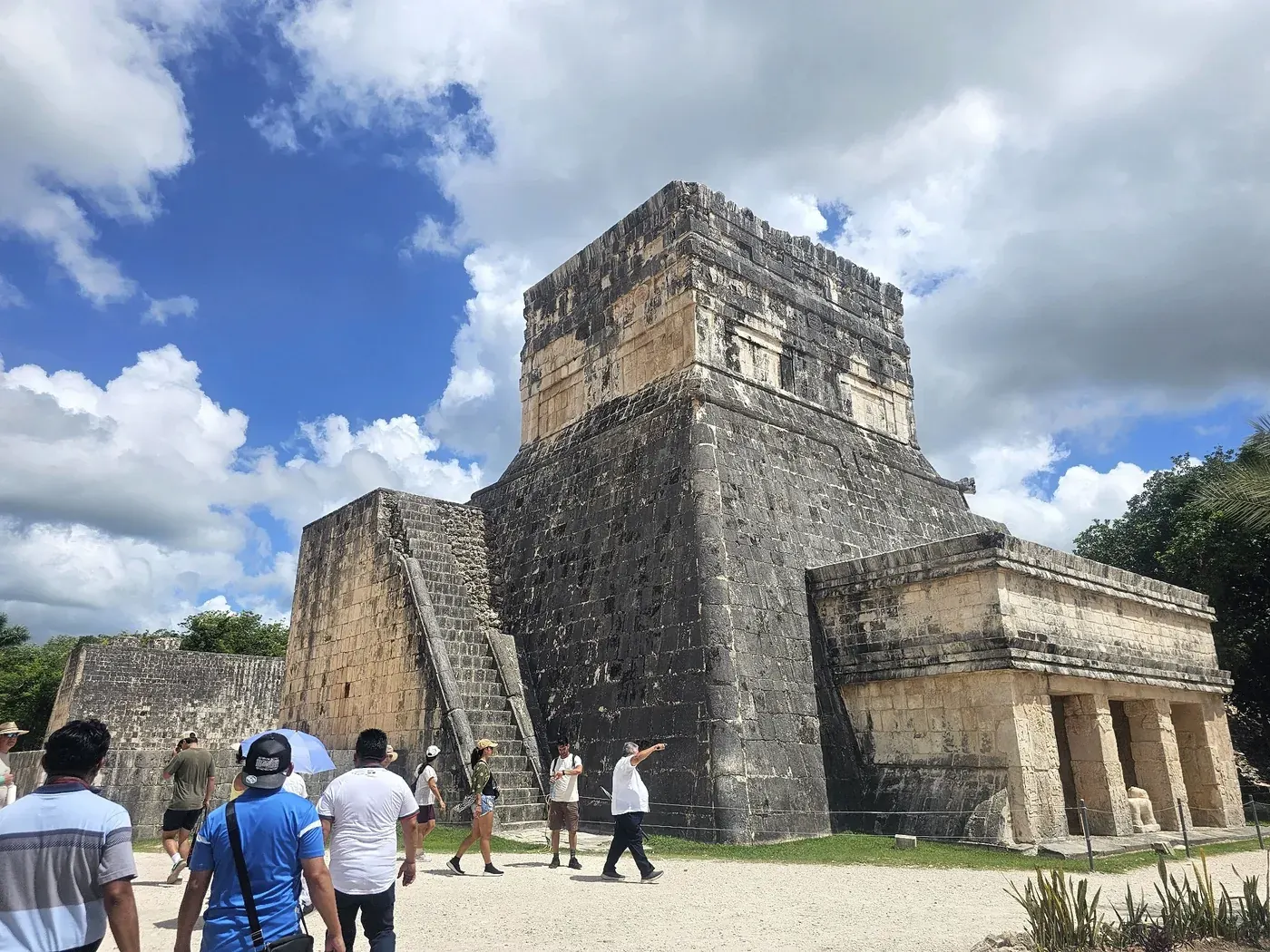 Temple of the Warriors at Chichen Itza with visitors walking nearby
