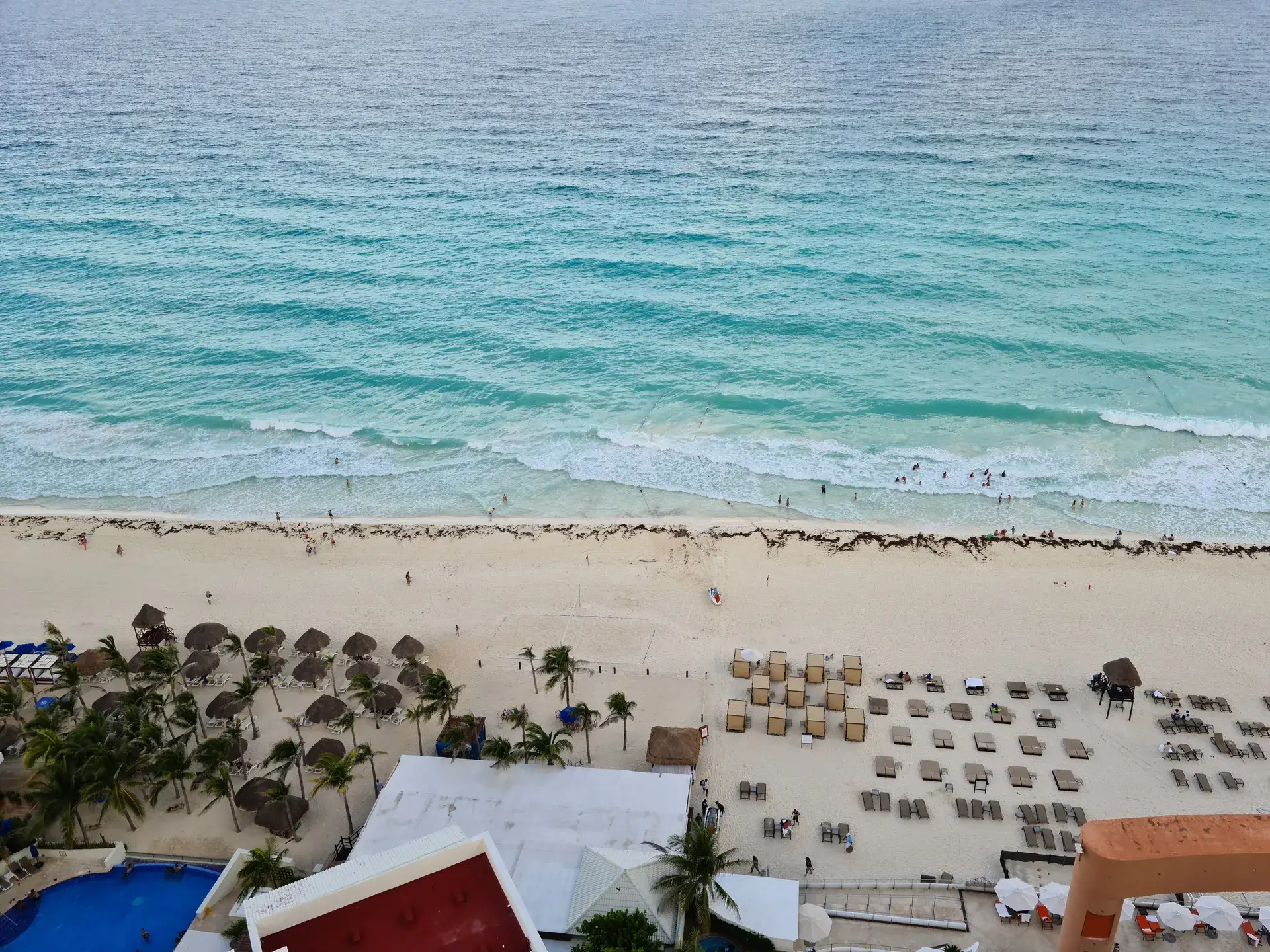 Aerial view of a Cancun beach with palapas and sun loungers along the shoreline, Mexico