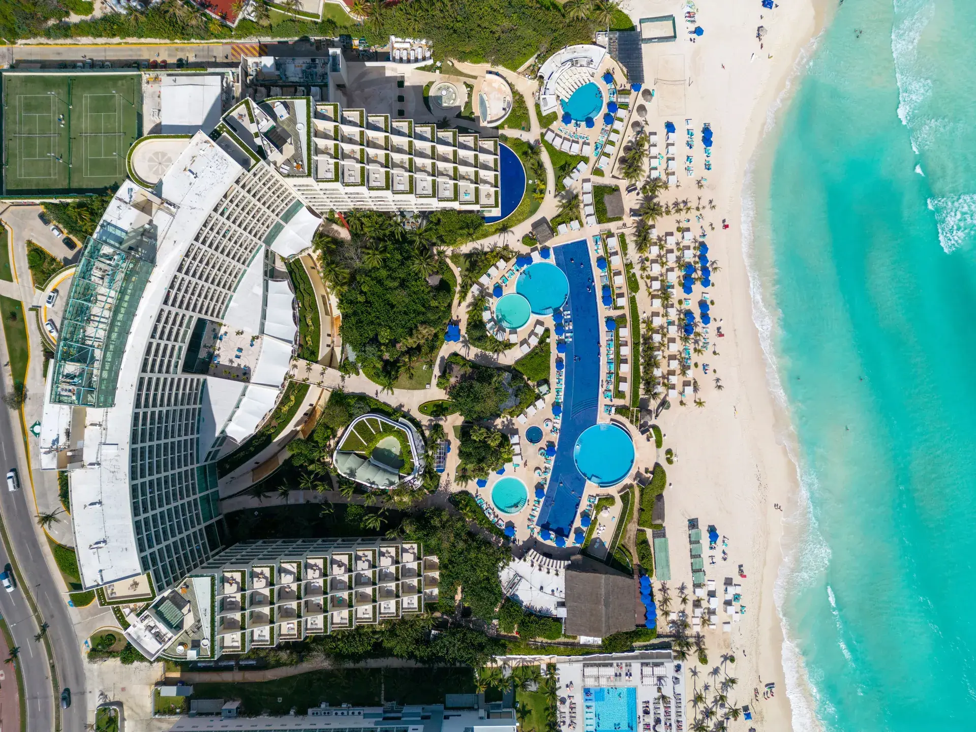 Overhead aerial view of a Cancun beach resort with pools beside turquoise Caribbean water, Mexico