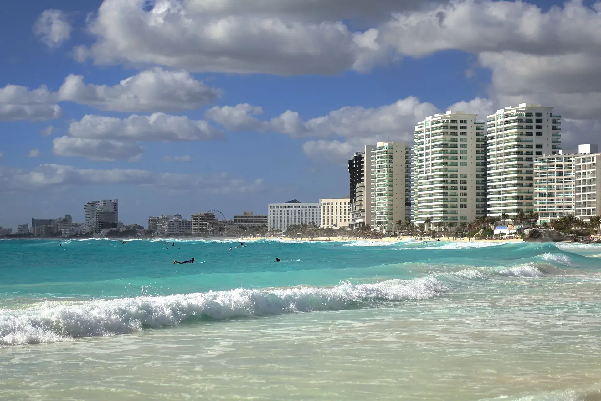 Cancun beach with ocean waves and the Hotel Zone skyline under a blue sky, Mexico