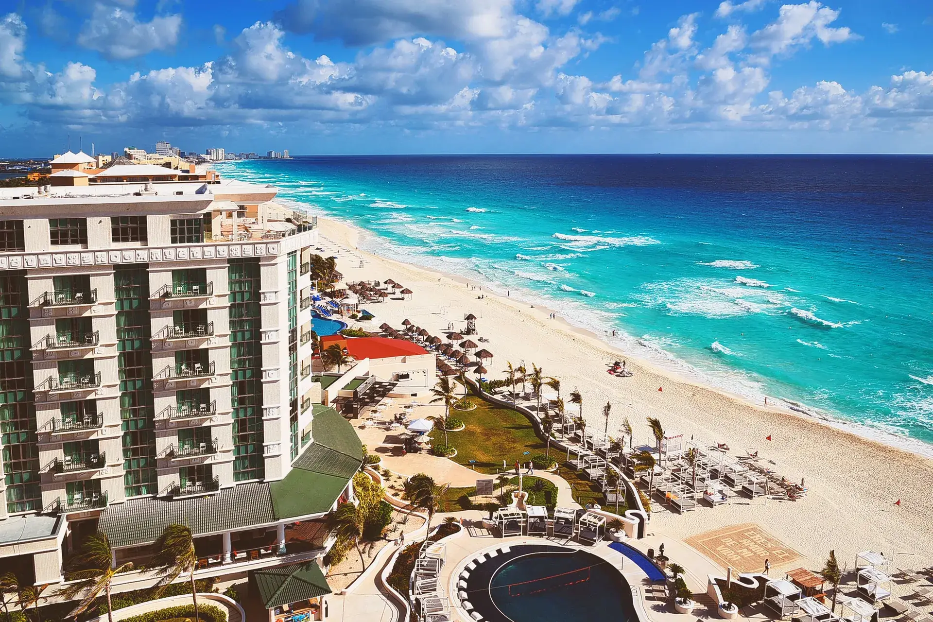 Elevated view of a Cancun beachfront resort with pools beside turquoise Caribbean water, Mexico