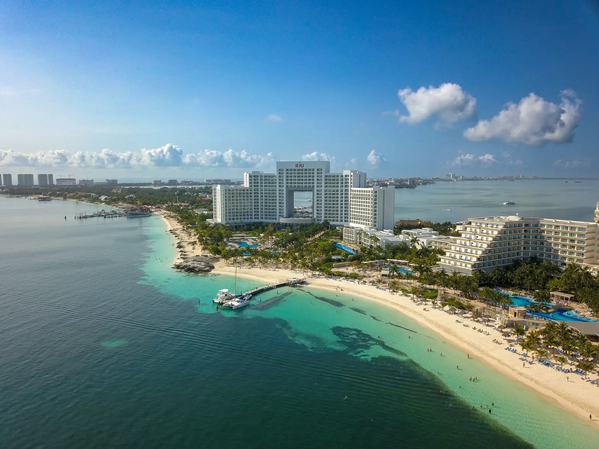 Aerial view of Punta Cancun beachfront resorts and calm turquoise bay with a catamaran, Cancun Mexico