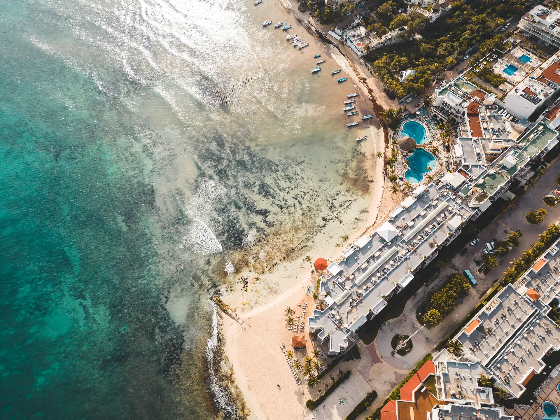 Aerial view of a Playa del Carmen beachfront resort with pools and sandy beach, Riviera Maya Mexico
