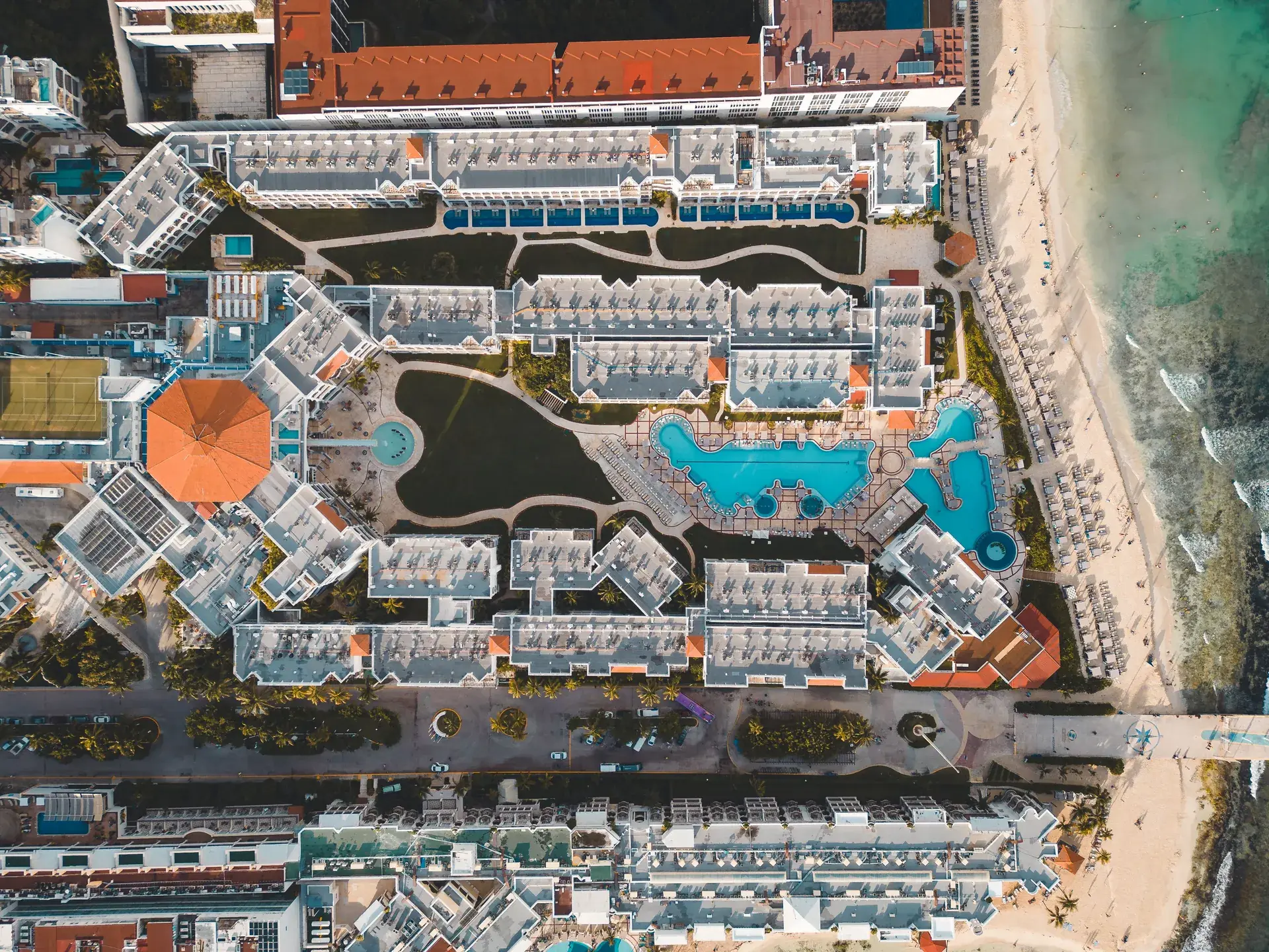 Overhead aerial view of a Playa del Carmen beachfront resort complex with pools, Mexico